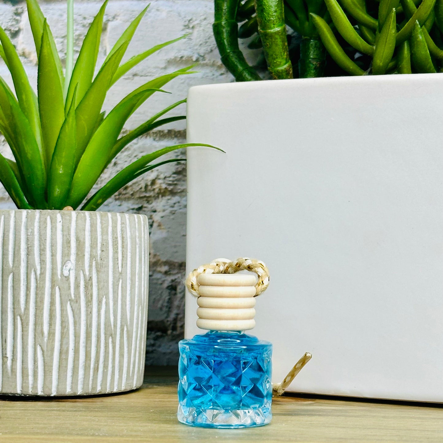 Blue diffuser with decorative design on a wooden surface with plants in the background.