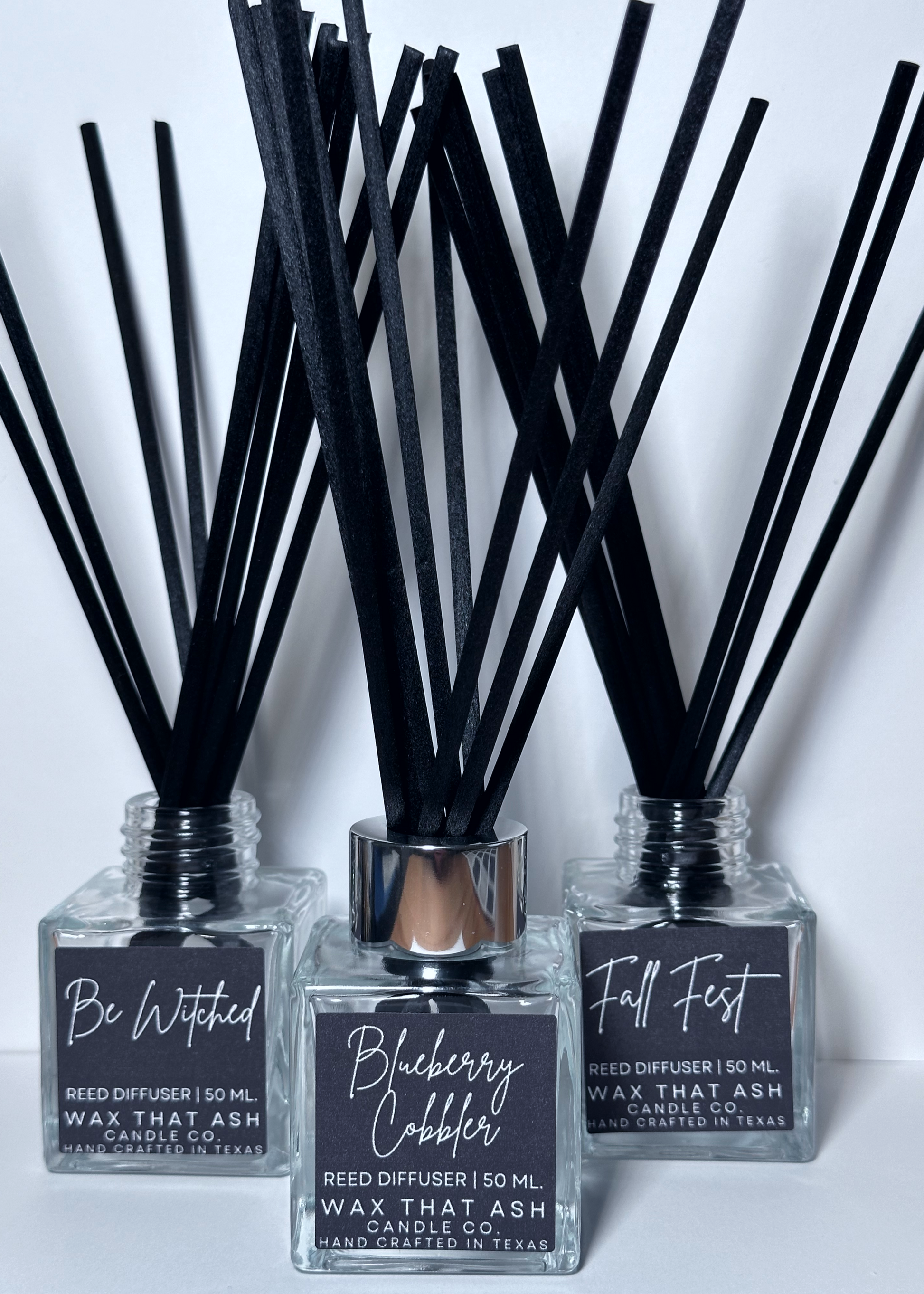 Reed diffusers with black sticks in clear bottles on a white background