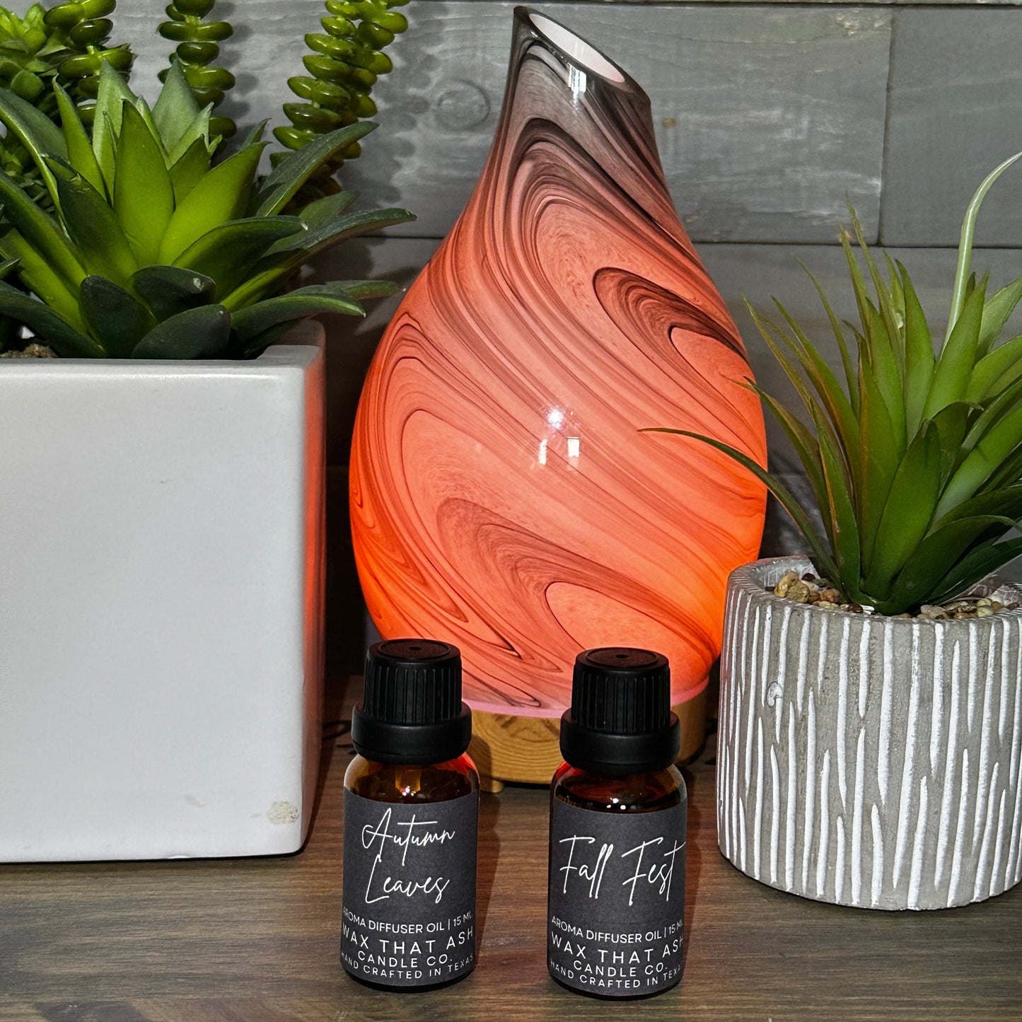 Decorative lamp with marbled design on a wooden surface with two small bottles and plants.