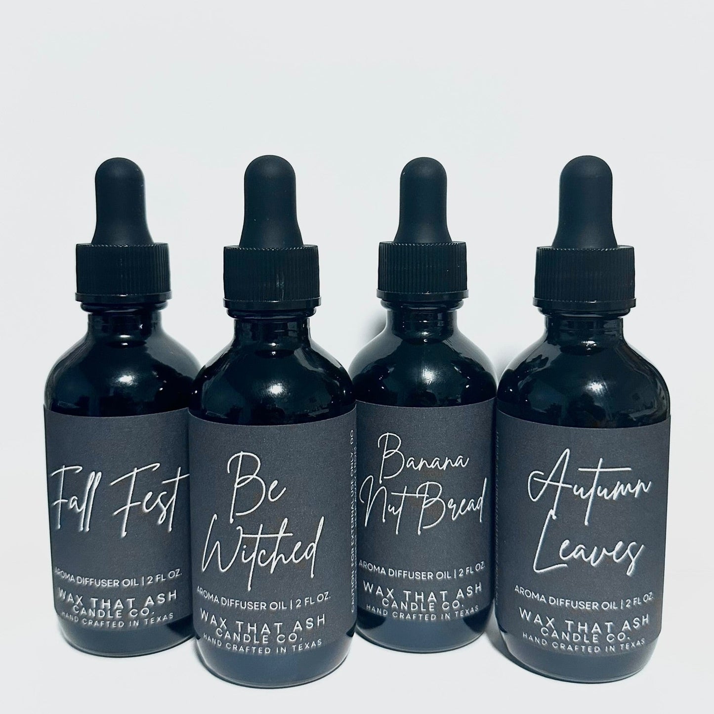 Four black bottles with dropper caps on a white background