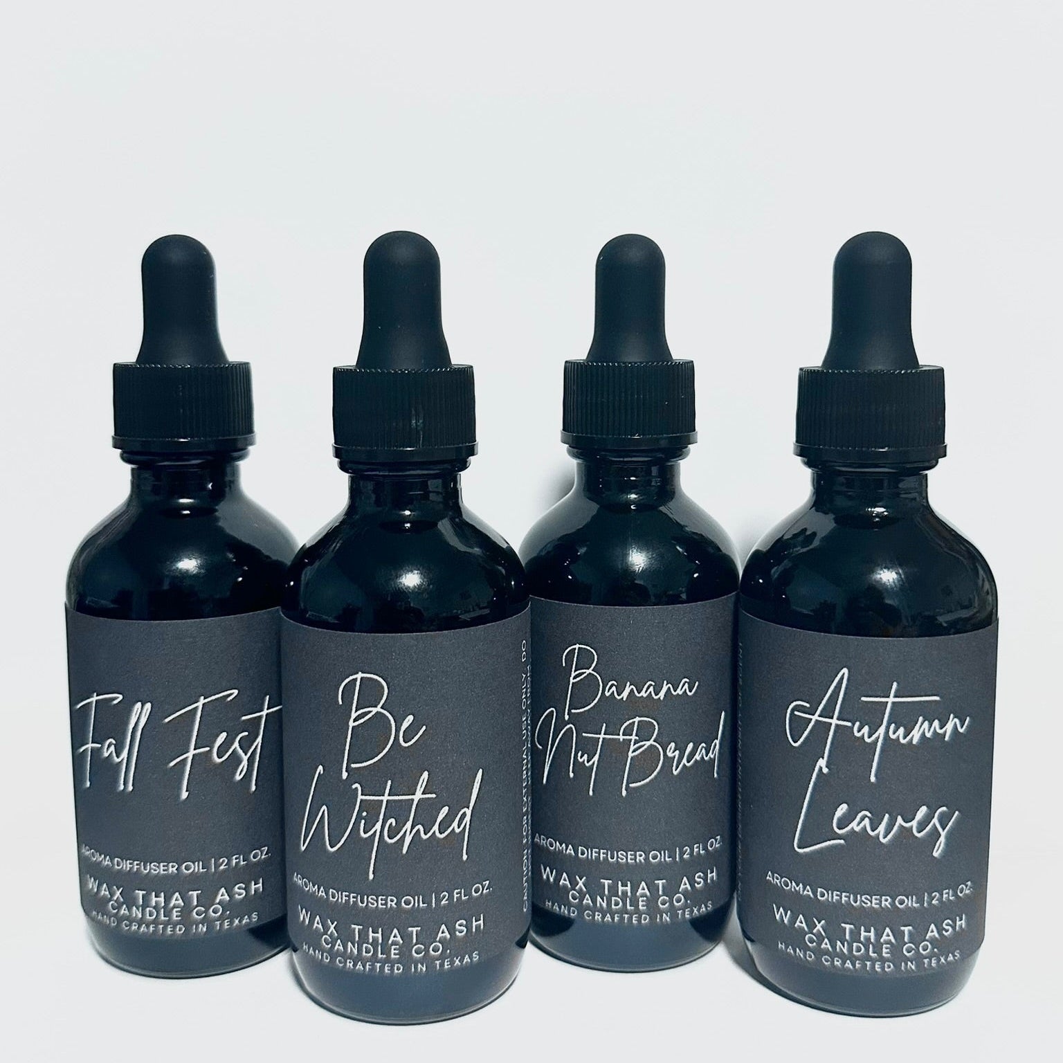 Four black bottles with dropper caps on a white background