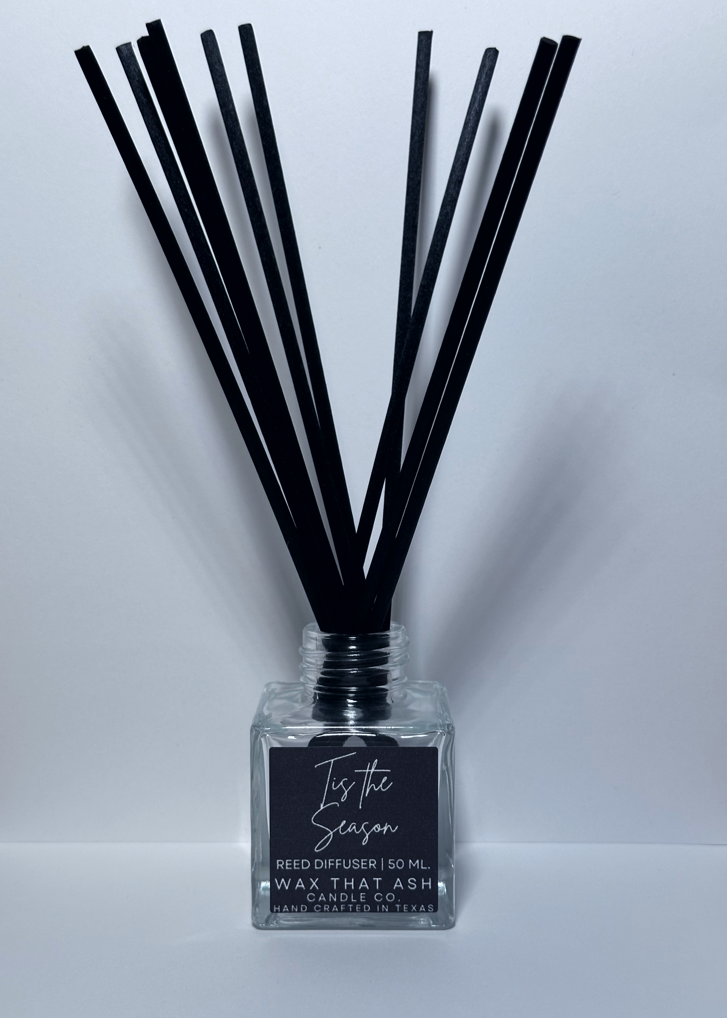 Reed diffuser with black sticks and a clear bottle labeled 'Is it the Season' on a white background.