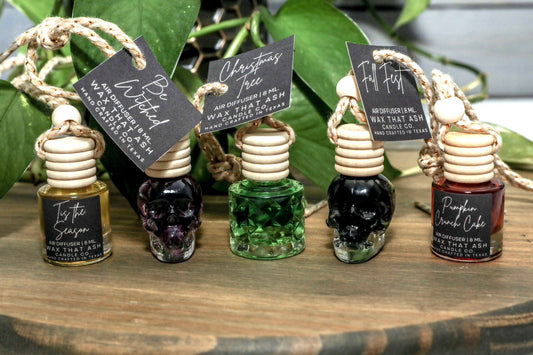 Set of small bottles with decorative labels on a wooden surface with greenery in the background.